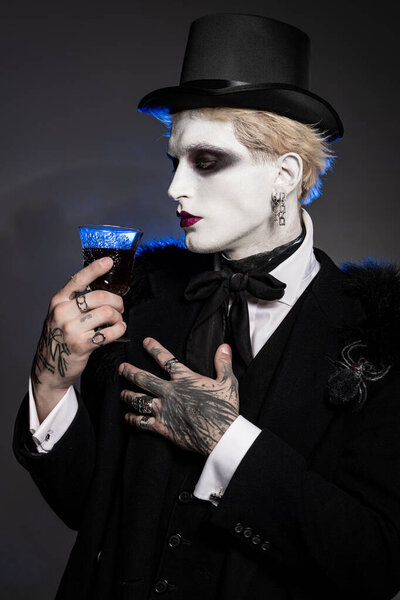 Young handsome man in captivating Halloween costume displays striking makeup and accessories.