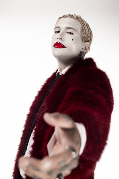 Handsome young man dressed as Joker captivates with iconic look during Halloween festivities.