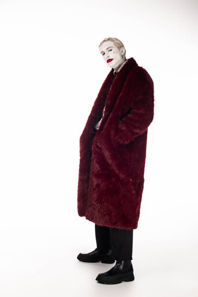 Dapper young man in vibrant Joker attire stands confidently, embodying Halloween spirit.