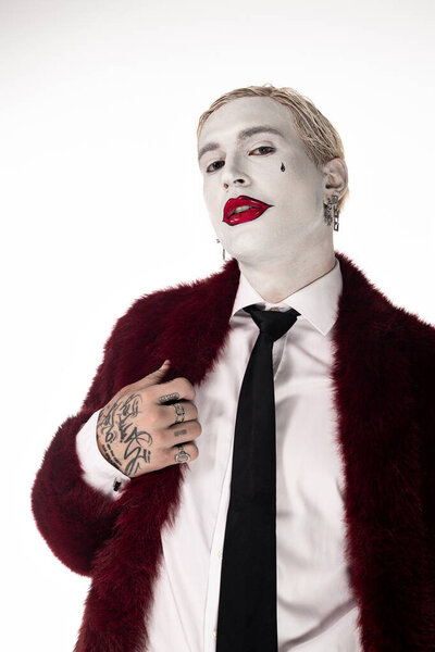 Handsome young man proudly displays his epic Joker costume during a Halloween event, full of spirit.