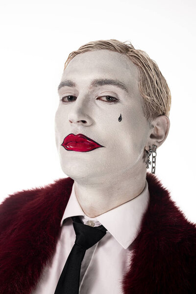 Handsome young man showcases a creative Joker costume with bold makeup and stylish attire.