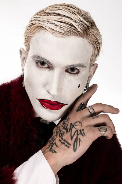 Handsome young man as the Joker sports a striking Halloween costume with bold makeup.