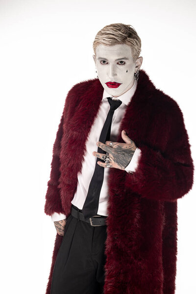 Handsome young man showcases an impressive Joker costume complete with makeup and stylish attire.