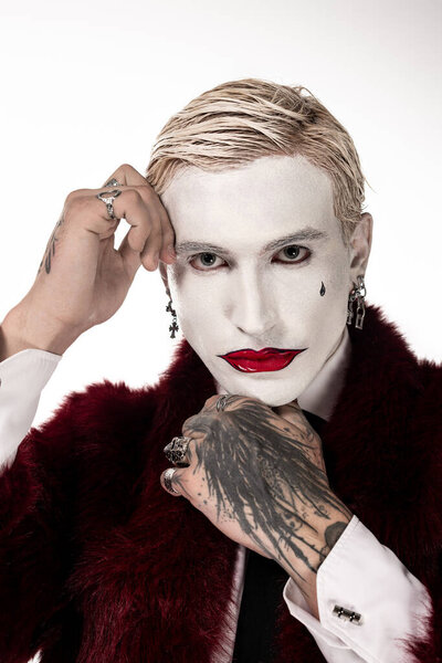 Young man showcases an epic Joker outfit with striking makeup and stylish accessories for Halloween.