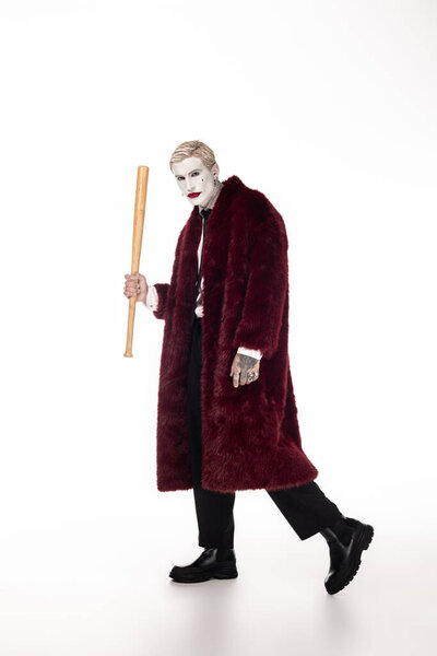 Handsome young man dressed as Joker walks confidently in vibrant costume, ready for Halloween fun.