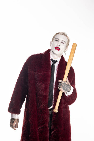 Молодой человек в костюме Джокера наслаждается Хэллоуином, держа летучую мышь в эпическом костюме.