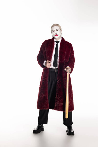 Young man showcases an impressive Joker costume while celebrating Halloween in a lively atmosphere.