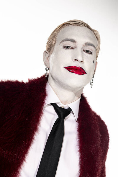 Молодой человек демонстрирует сложный костюм Джокера, подчеркивая его художественный макияж и наряд.