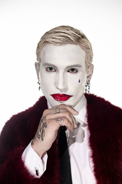 Молодой человек уверенно позирует в ярком костюме Джокера на Хэллоуин.