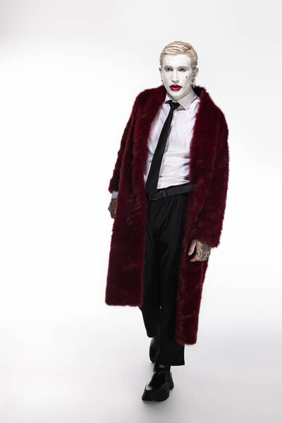 A young man in a striking Joker costume walks confidently, embracing the Halloween spirit.