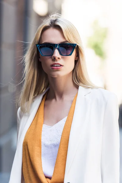 Portrait of beautiful young blonde woman in sunglasses looking at camera — Stock Photo