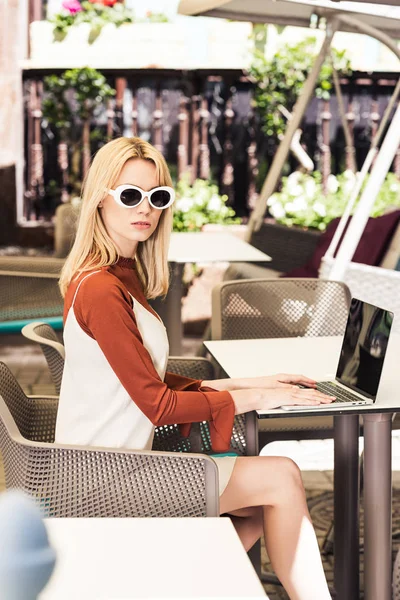 Belle jeune femme en lunettes de soleil à l'aide d'un ordinateur portable — Photo de stock