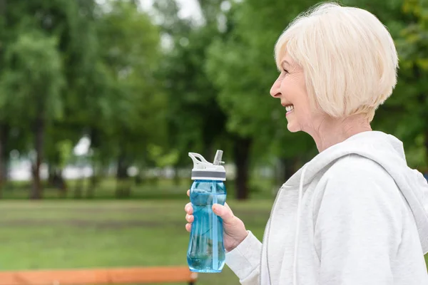 Profile portrait of happy senior woman holding sport bottle — Stock Photo