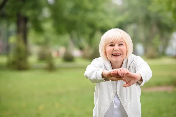 Anziana sportiva che si esercita sul prato verde nel parco — Foto stock