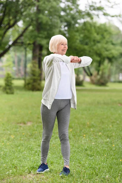Старша біла спортсменка займається на зеленому газоні в парку — стокове фото