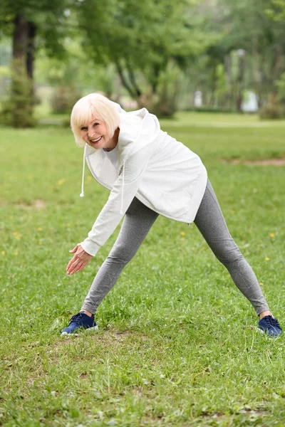 Femme athlétique senior dans l'entraînement de vêtements de sport sur pelouse verte dans le parc — Photo de stock