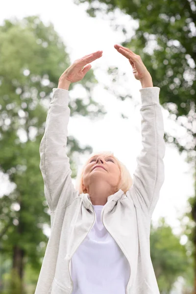 Senior athletic woman exercising and stretching in park — Stock Photo