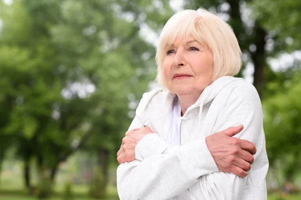 Femme âgée avec les cheveux gris congelés dans le parc — Photo de stock