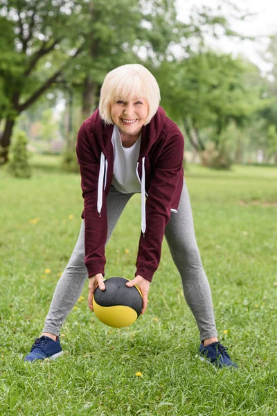 Formazione della donna anziana con palla medica nel parco — Foto stock