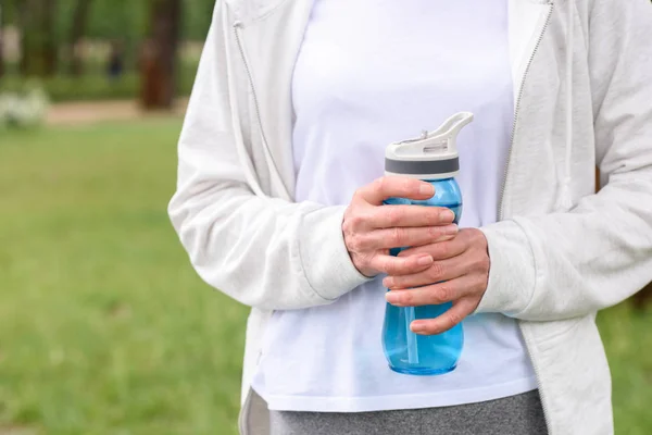Cropped view of sportswoman holding sport bottle with water — Stock Photo