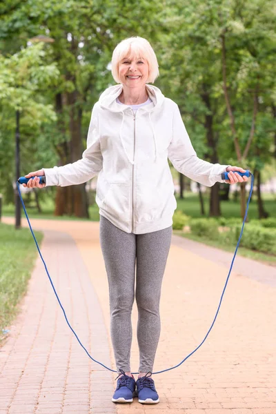 Senior sportswoman training with jump rope in park — Stock Photo