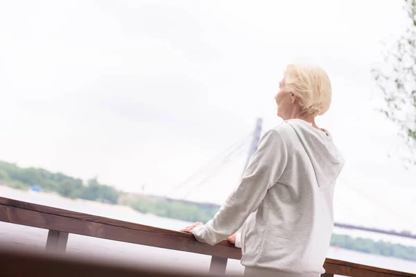 Femme debout à des balustrades en bois près de la rivière — Photo de stock