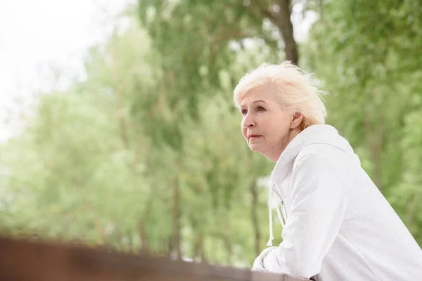 Senior woman standing near railings in park — Stock Photo