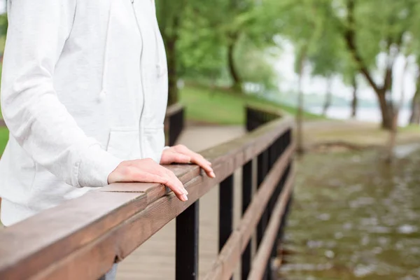 Cropped view of woman standing alone near railings in park — Stock Photo