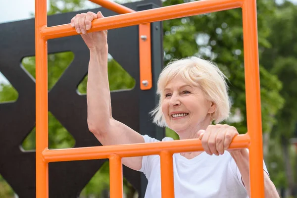Senior sportswoman with grey hair training on sports ground — Stock Photo