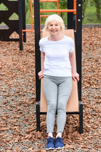 Lächelnde Seniorin trainiert auf Sportplatz im Freien — Stockfoto