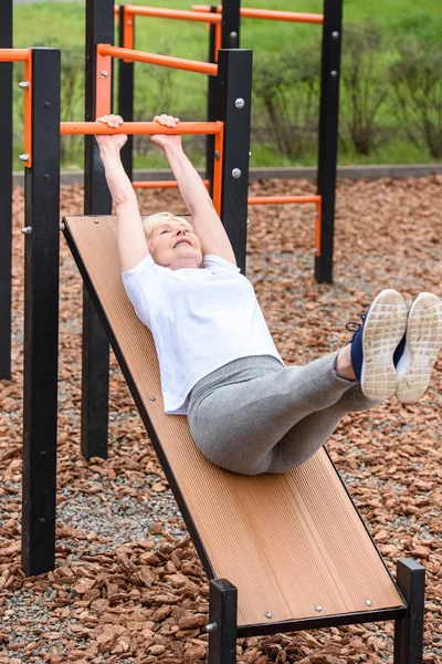 Deportista senior haciendo abdominales en campo de deportes - foto de stock