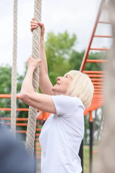 Mulher idosa exercitando com corda no chão de esportes — Fotografia de Stock