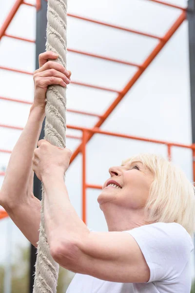 Senior sportswoman exercising with rope on sports ground — Stock Photo