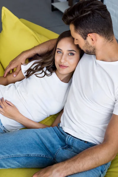 High angle view of happy young couple sitting together on couch, woman looking at camera — Stock Photo