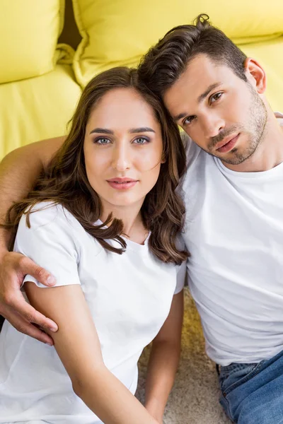 High angle view of beautiful young couple embracing and looking at camera at home — Stock Photo