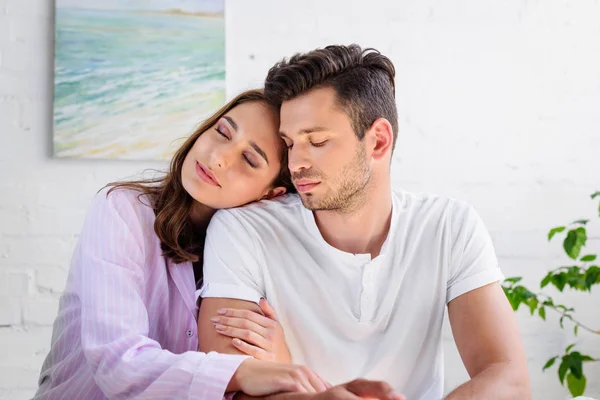 Happy sensual young couple in pajamas sitting together at home — Stock Photo