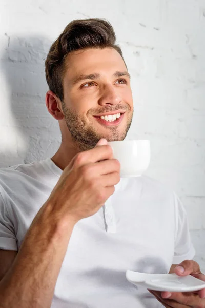 Guapo sonriente joven bebiendo café por la mañana en casa - foto de stock