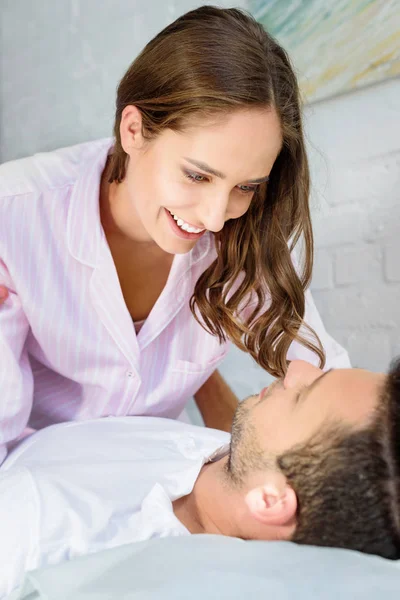 Glückliches junges Paar schaut sich zu Hause im Bett an — Stockfoto