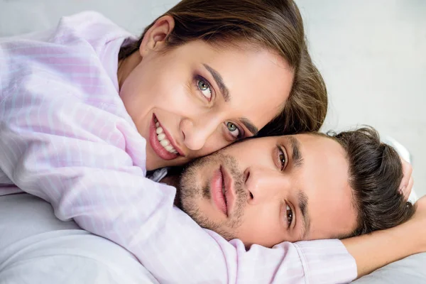 Beautiful lovers hugging on bed and looking at camera — Stock Photo