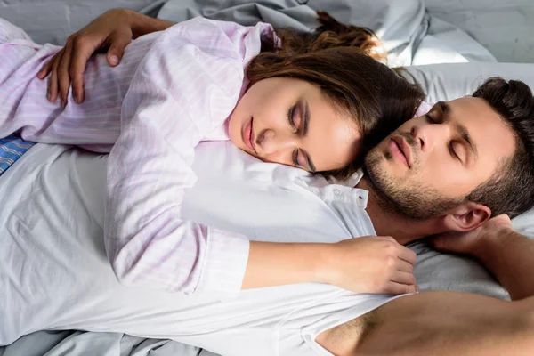 Jovem belo casal abraçando e dormindo na cama — Fotografia de Stock