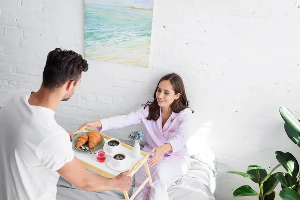Jovem casal feliz tomando café da manhã na cama juntos — Fotografia de Stock