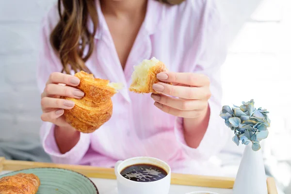 Partial view of woman in pajamas having croissant and coffee for breakfast — Stock Photo