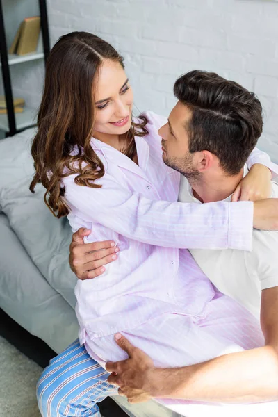 Moglie sorridente seduta sulle ginocchia del marito e lo abbraccia — Foto stock