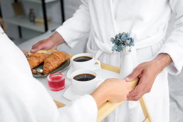 Vista recortada de la bandeja de celebración de pareja con croissants y café para el desayuno - foto de stock