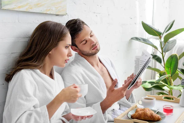 Pareja joven con café para el desayuno leyendo el periódico juntos - foto de stock