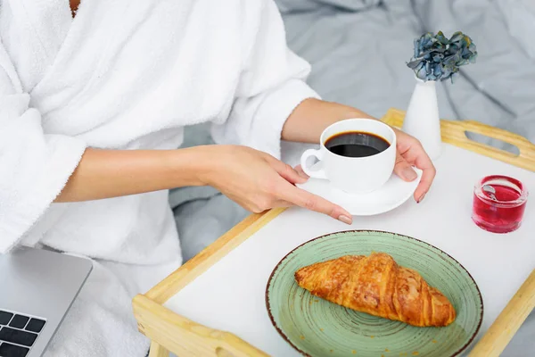 Cropped view of woman in bathrobe having breakfast with coffee and croissant — Stock Photo