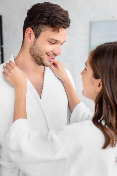 Happy couple in white bathrobes standing together in morning — Stock Photo