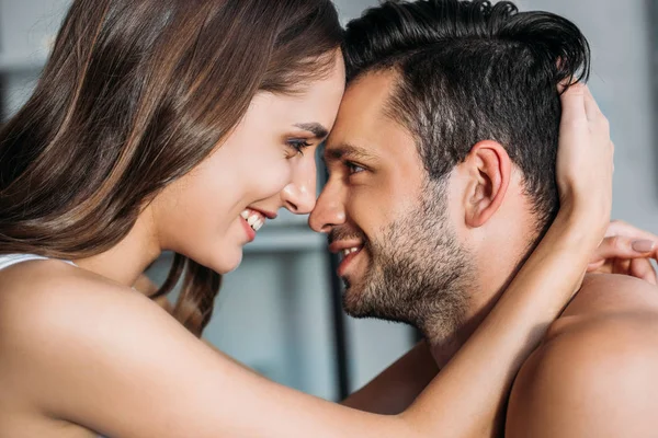Sensual sonriente pareja tocando con frentes y mirándose en casa - foto de stock