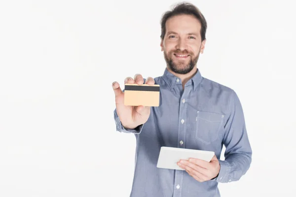 Portrait of smiling man with digital tablet showing credit card isolated on white — Stock Photo