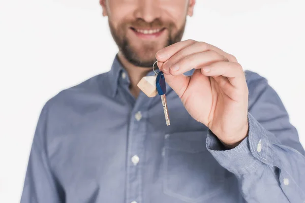 Обрізаний знімок усміхненого чоловіка, що показує ключ від нового будинку в руці ізольовано на білому — стокове фото